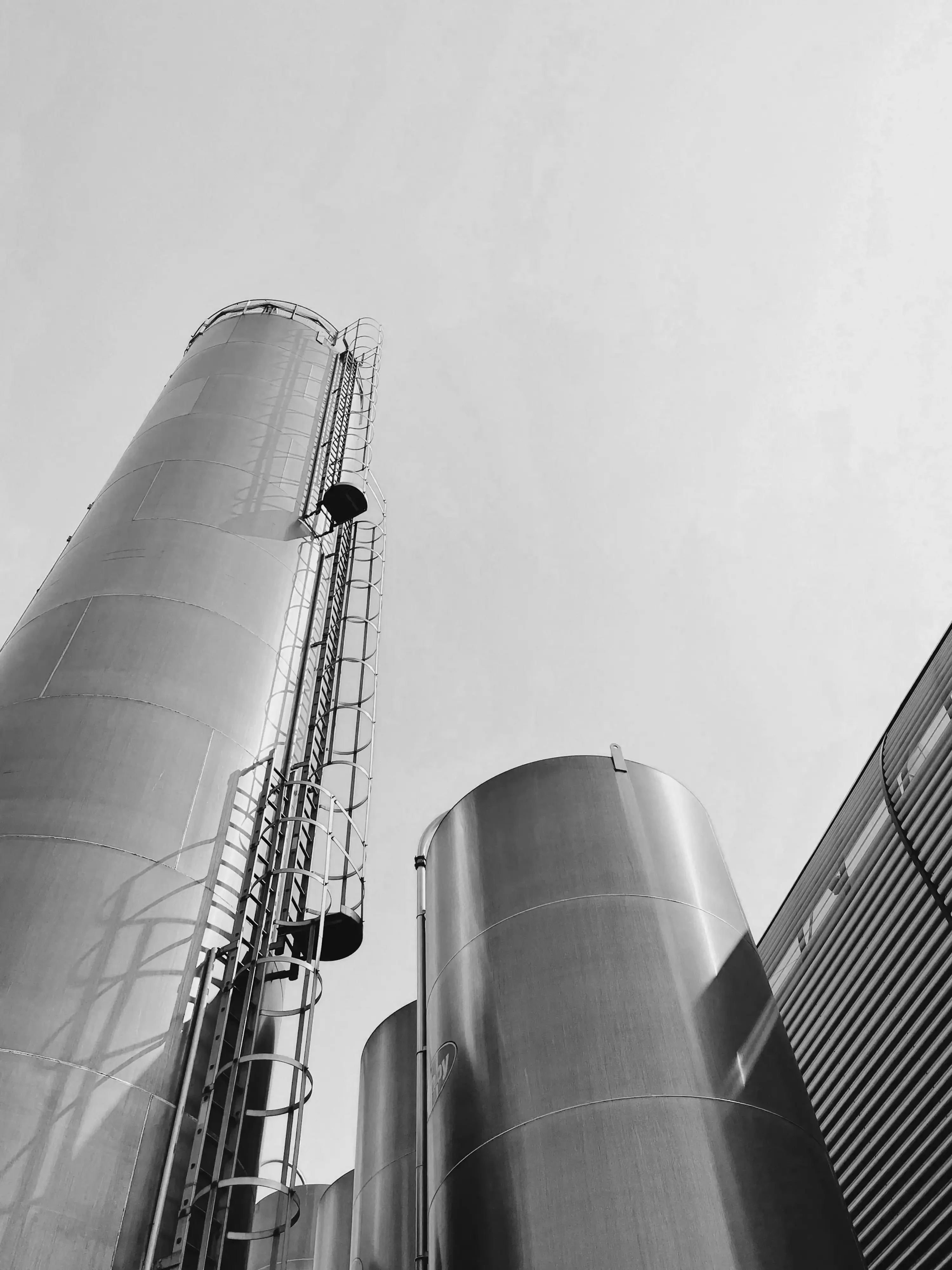 Industrial silo towers seen from below against a bright sky