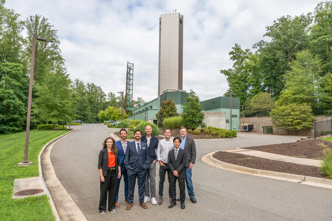 Applied team members standing in front of  the IST in the background from a farther away angle 